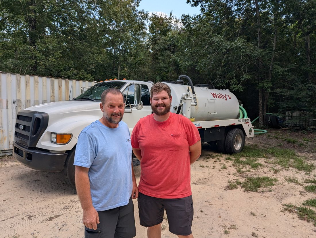 Two of the Wally's Septic crew standing in front of the pump truck